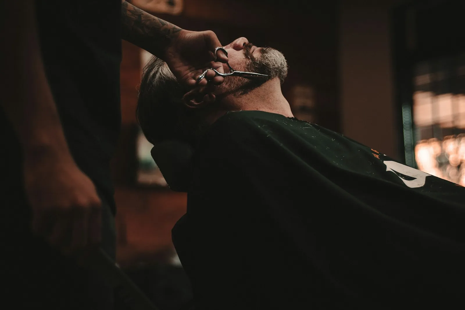 Barbier rasiert einen Kunden mit dem Messer, warmes Salonlicht