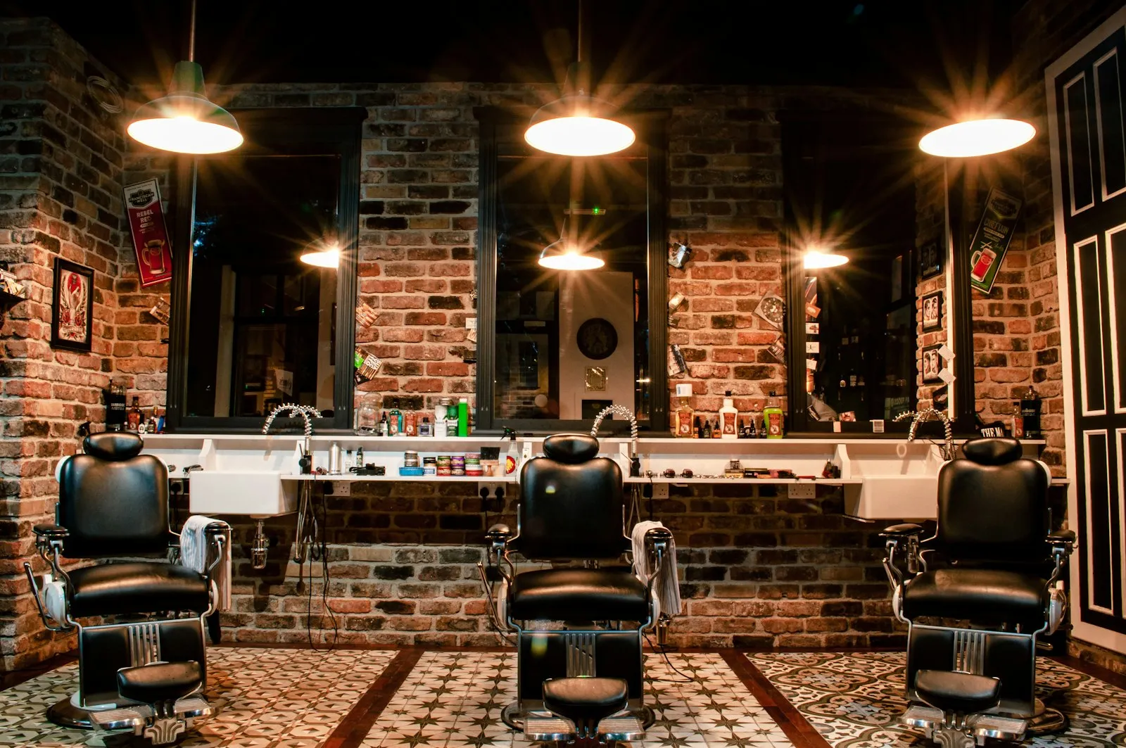 Blick in den Salon: drei Barbierstühle vor Spiegeln und warmem Licht