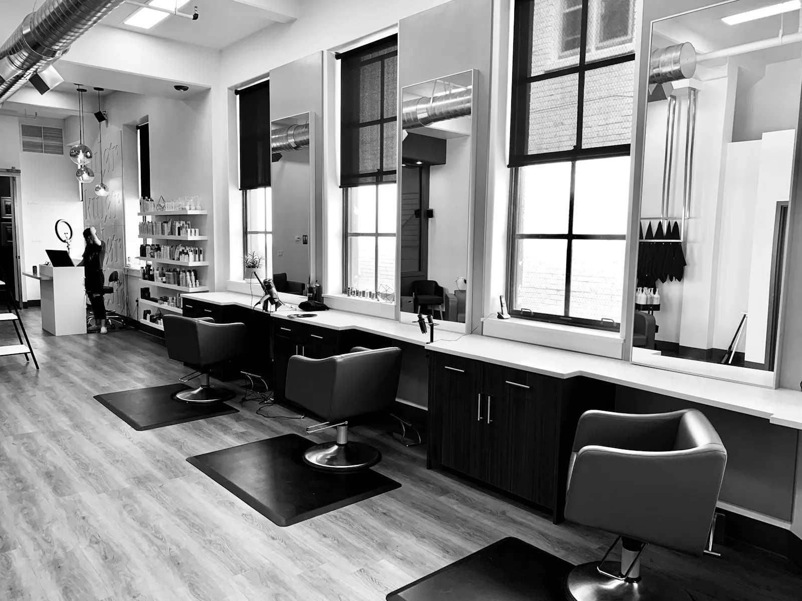 Heller Salon mit Stühlen und großen Fenstern in Schwarz-Weiß